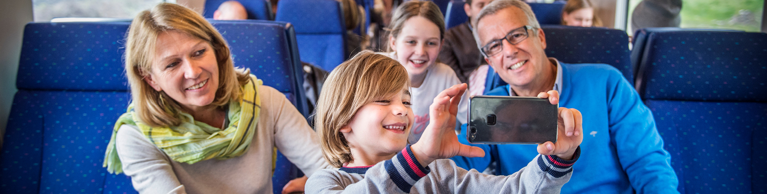 Des grands-parents avec leur enfant prenant un selfie dans un train belge