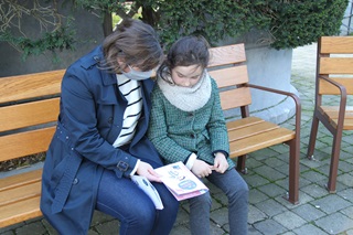 Une maman assise avec sa fille regardant le carnet d'aventure