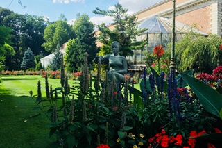 Une serre et une statue dans un parc fleuri en été